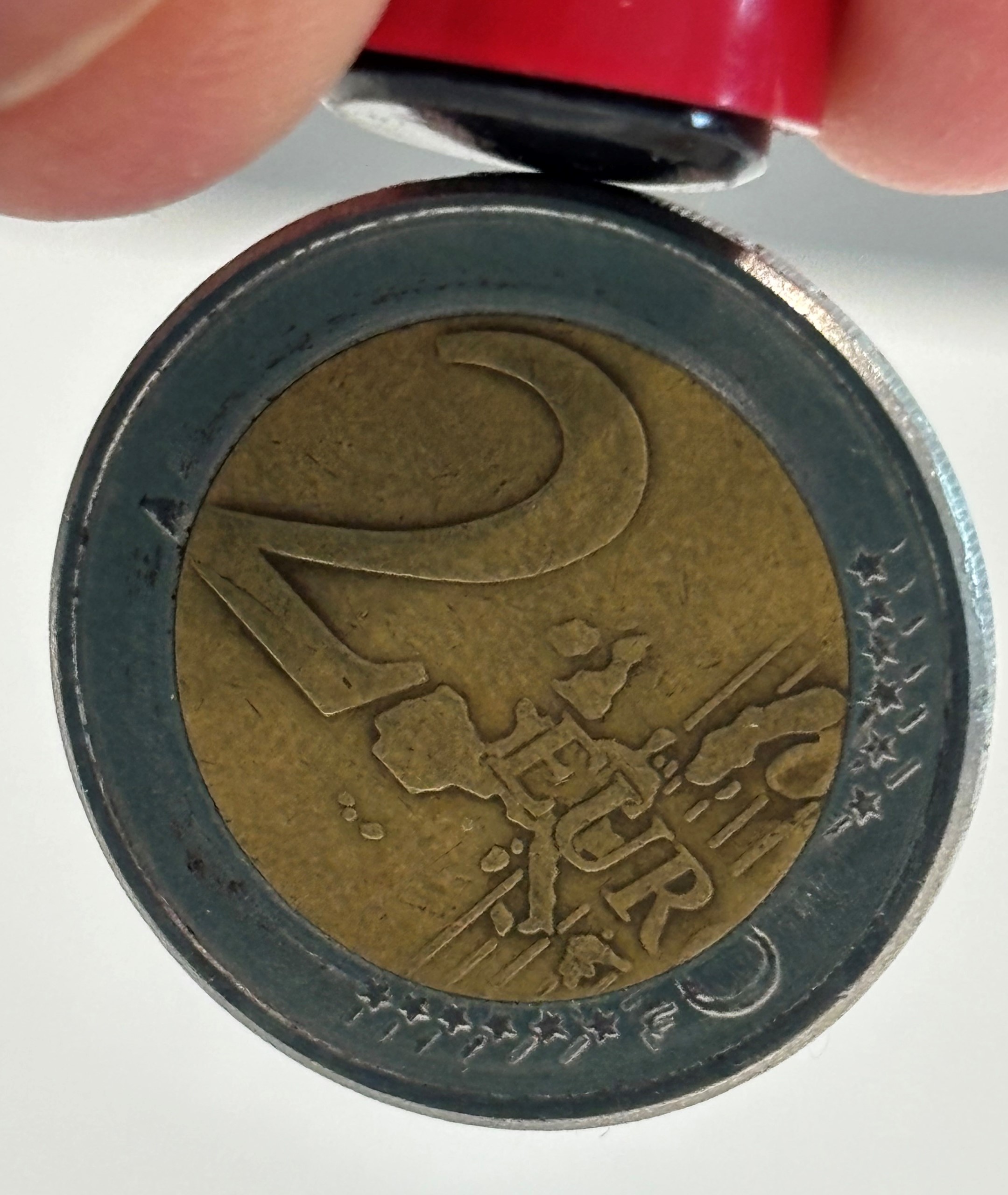 Eine 2-Euro-Münze haftet mit dem Rand an einem Magneten
